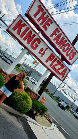 woman standing in front of pizzeria sign